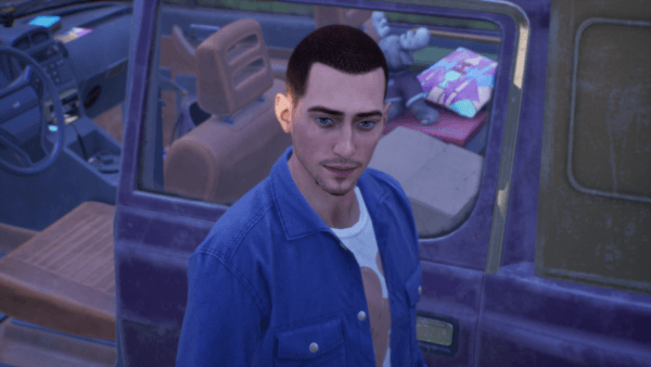 A young white man with close-cropped brown hair stands in front of a truck full of belongings.